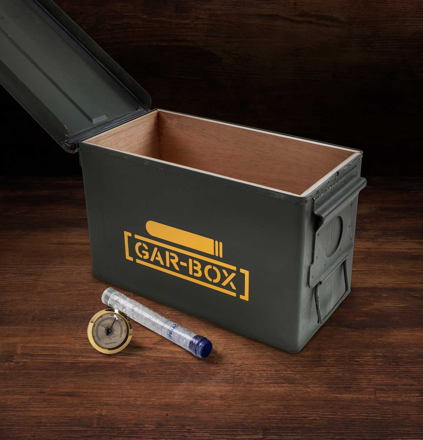 Gar-Box humidor open on table showing the cedar lined box and the DryMistat humidifier device and the removable brass hygrometer in front of box